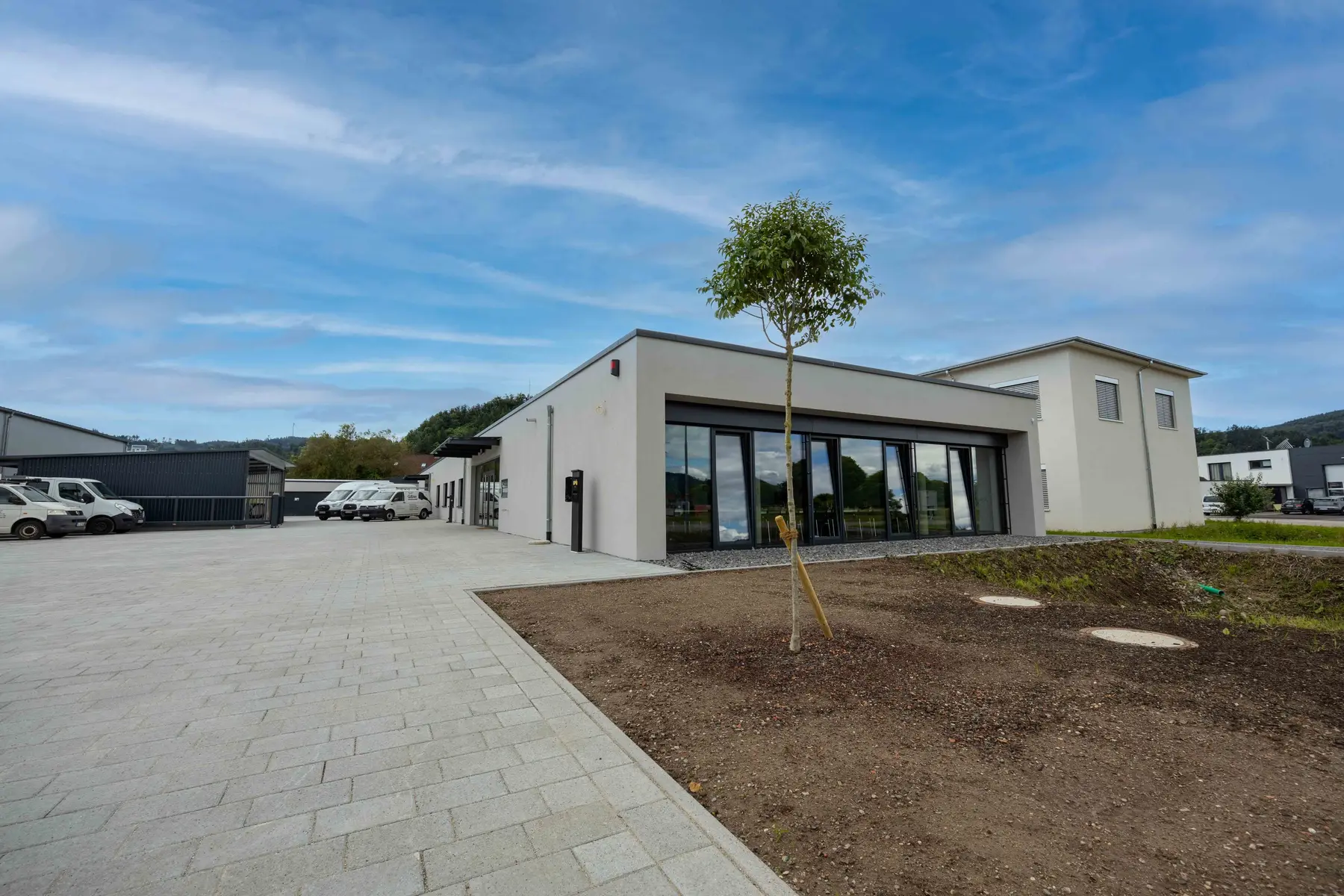 Firmengebäude von SEB-Solar in Berghaupten mit großer Glasfront, davor der gepflasterte Hof und weiße Transporter