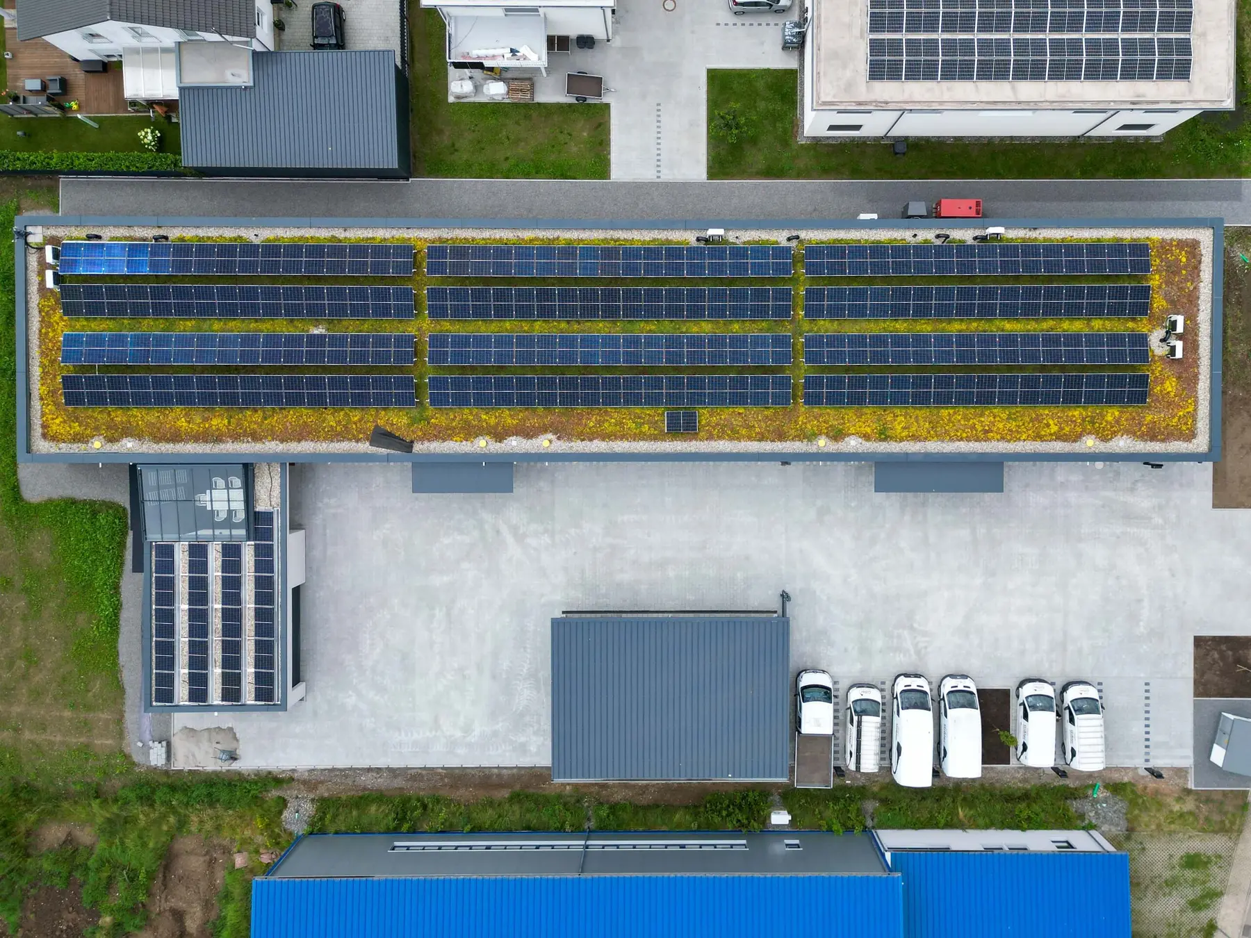 Betriebsgebäude von SEB-Solar in Berghaupten aus der Luft: Photovoltaikanlage in vier Reihen auf dem begrünten Flachdach, davor der Hof mit weißen Fahrzeugen