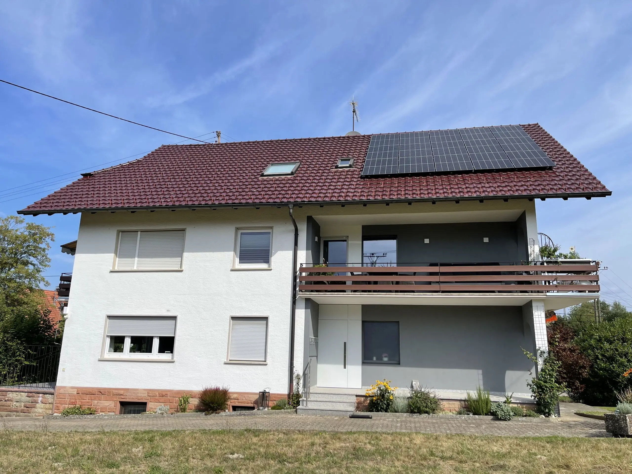 Wohnhaus mit mehreren Einheiten und Photovoltaikanlage auf dem roten Ziegeldach