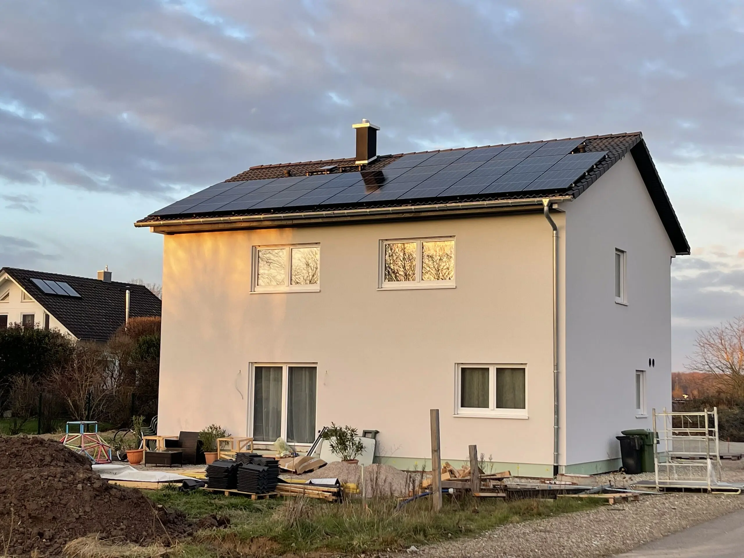 Einfamilienhaus mit voll belegter Photovoltaikanlage auf dem Satteldach im Abendlicht