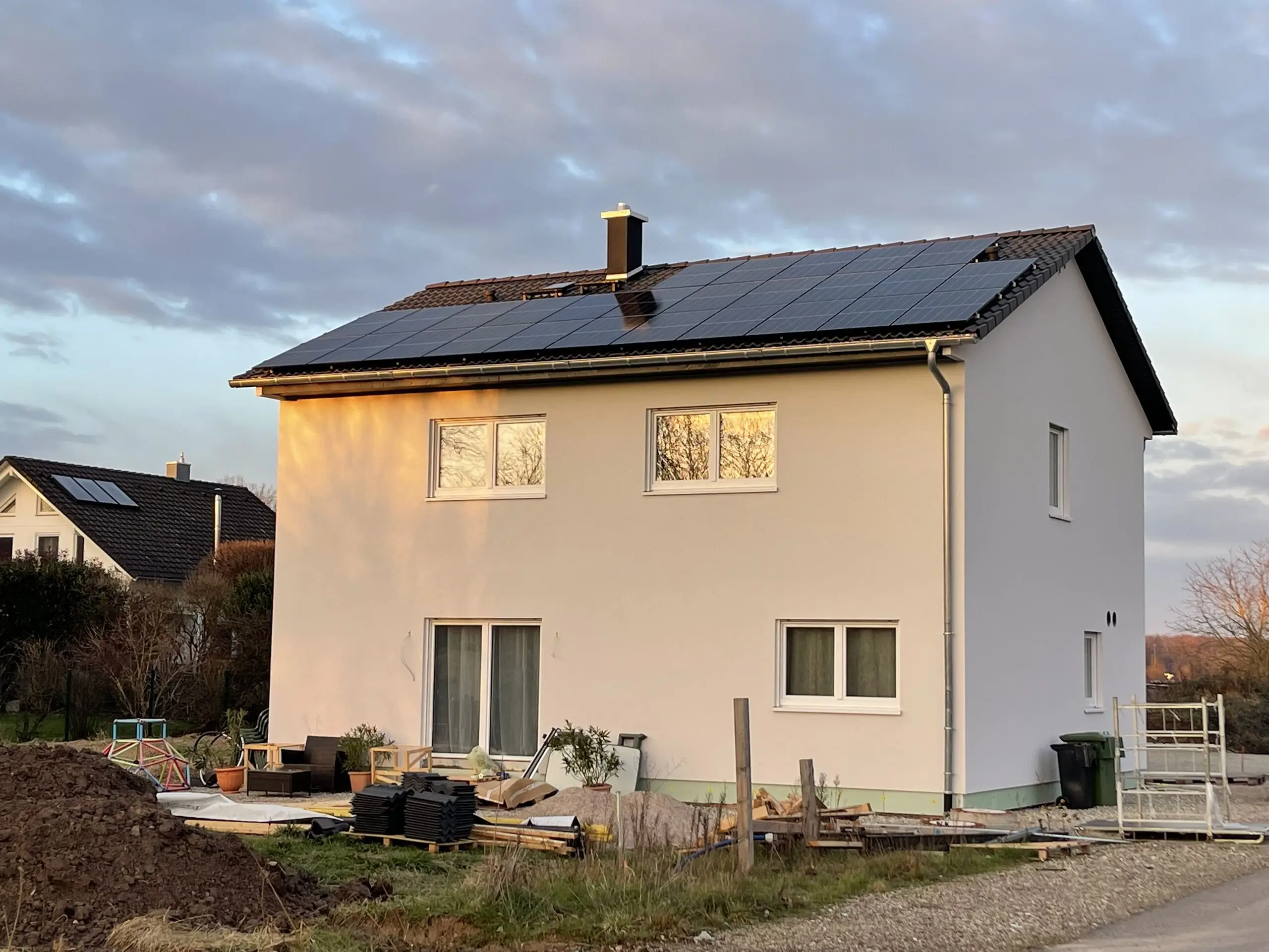 Einfamilienhaus mit voll belegter Photovoltaikanlage auf dem Satteldach im Abendlicht
