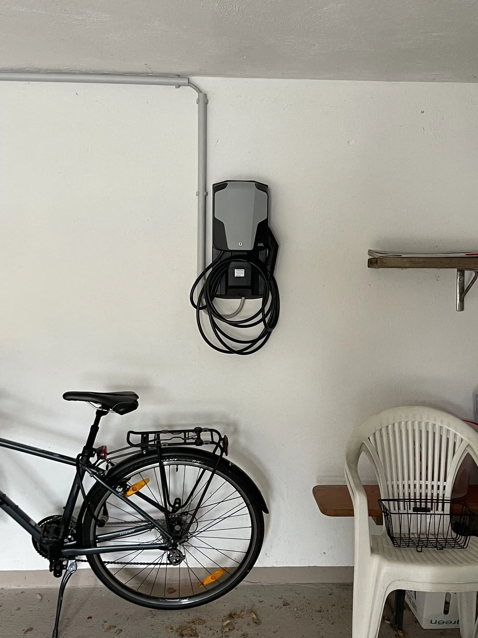 Wallbox mit aufgehängtem Ladekabel an der Wand einer Hausgarage