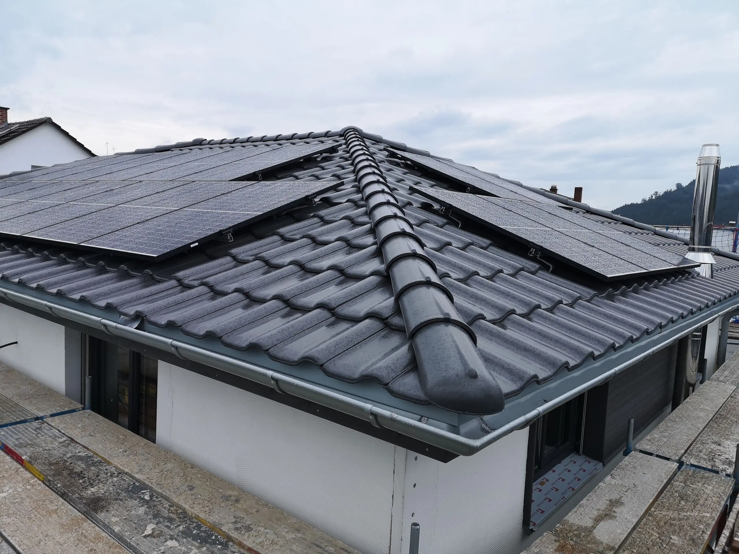 Photovoltaikanlage auf dem Walmdach eines Neubaus, aufgenommen vom Gerüst